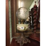 Victorian oil lamp on cast iron base with painted bowl and etched football shade.