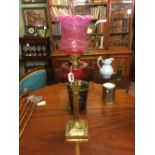 Brass oil lamp with corinthian column with ruby glass bowl and ruby shade.