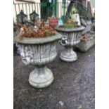 Pair of composition garden urns the handles terminsting with lion's masks.