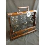 19th. C. oak Tantalus with three cut glass decanters with silver label.