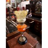 Victorian oil lamp with brass column and orange end of the day glass bowl.