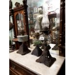 Three Victorian oil lamps with decorative cast iron bases.