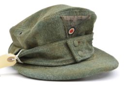 A Third Reich green ski cap, with one piece woven eagle and cockade badge. GC (small hole in