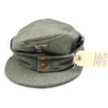 A Third Reich grey/green felt ski cap, with one piece Bevo woven badge, cut around and zig zag