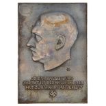 A Third Reich bronzed metal plaque bearing Hitler’s profile, inscription “Die Voraussetzung Zur