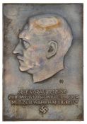 A Third Reich bronzed metal plaque bearing Hitler’s profile, inscription “Die Voraussetzung Zur