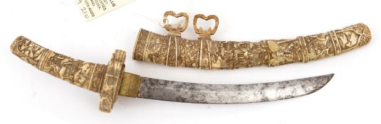 A miniature Japanese bone sword, curved blade 6”, the hilt and sheath composed of sections, deeply