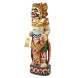 A gilt and colour painted kris stand, in the form of a standing demon headed figure, provision for