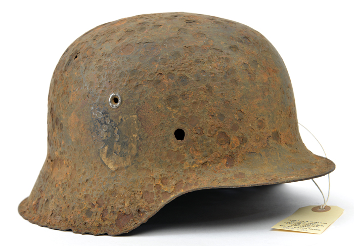 An excavated Third Reich M42 steel helmet, with remains of SS and party decals, heavily corroded