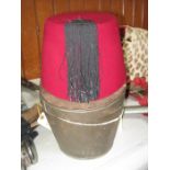 An old Egyptian red fez with black tassel, silk and leather lined, in its original tin case with