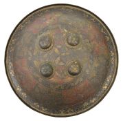An Indian brass circular shield, 4 central bosses, turn over rim, lightly engraved with stylized,