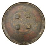 An Indian brass circular shield, 4 central bosses, turn over rim, lightly engraved with stylized,