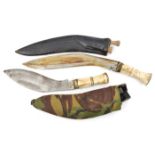 2 kukris, bone hilts, one in black leather sheath, the other camouflage material, with companion