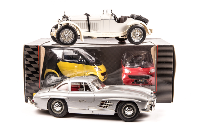 A quantity of Mercedes-Benz models. 1:18 Maisto A-Class in red, and a Smart Car in yellow with spare