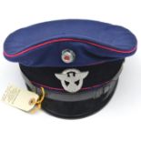 A Third Reich Police peaked cap, Prussian blue with black velvet band, red piping, black fibre