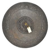 A decorative cast iron circular shield, stylized figures to centre, and around the rim, with