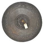 A decorative cast iron circular shield, stylized figures to centre, and around the rim, with