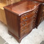 A REPRODUCTION BOW FRONT CHEST OF DRAWERS WITH SLIDE