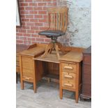 A 1920s stepped pedestal oak office desk with drawers on the right and tambour fronted slides on the