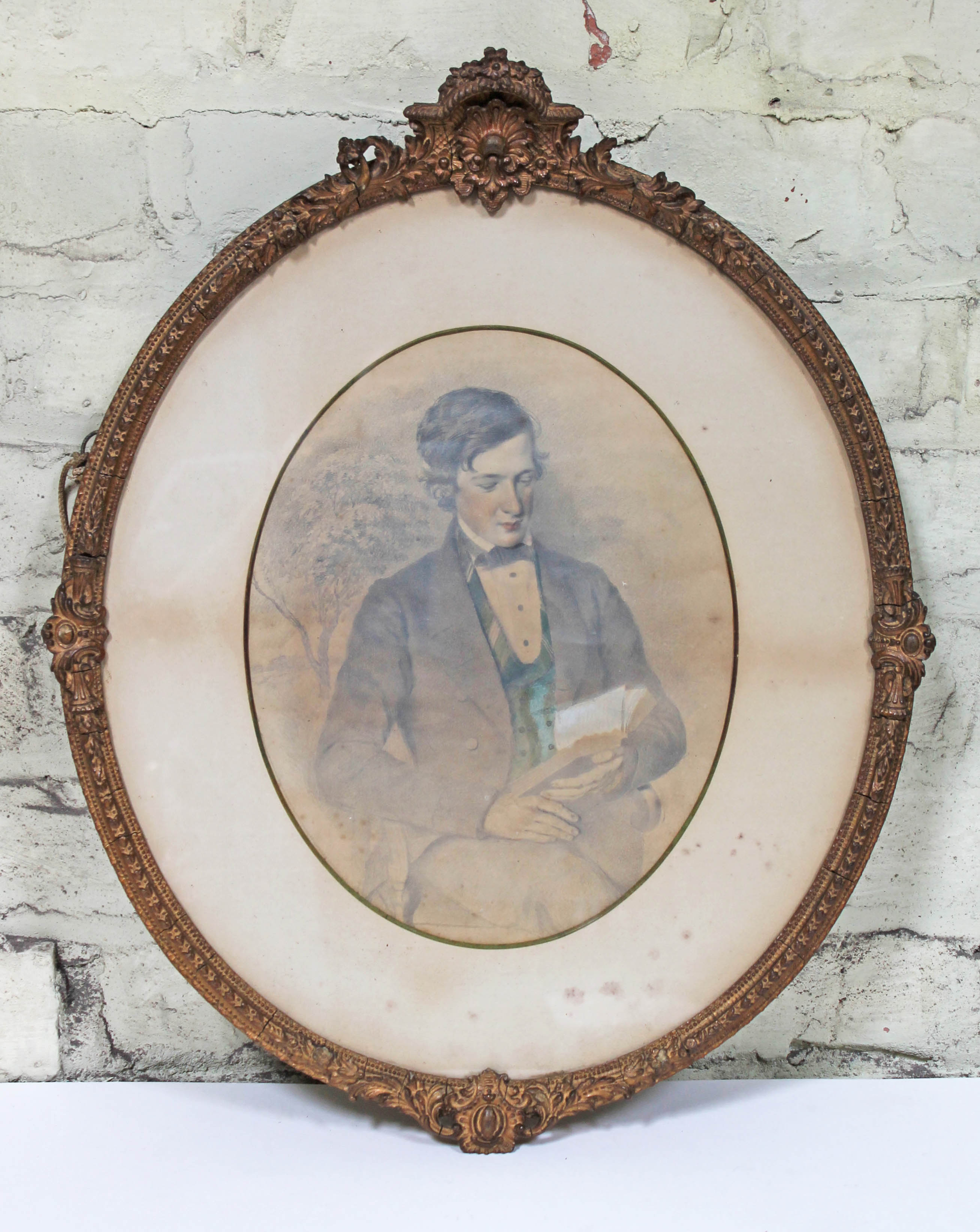 19th Century School, pencil drawing of a young gentleman sat reading, oval 24cm x 30cm, glazed and