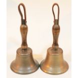 A pair of brass bells with turned wooden beech handles and leather loops, height 33cm.