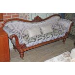 A William IV mahogany framed settee with scroll arms and shaped carved back, turned legs and brass