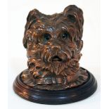 A copper inkwell formed as a Westie dog with glass eyes on turned wooden base, height 13cm.