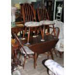 An Ercol dark elm and beech drop leaf table and four chairs.