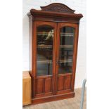 A late Victorian cabinet bookcase with carved domed and dentilated cornice, arched glazed and