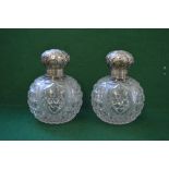 Pair of cut glass silver topped scent bottles the lids having embossed decoration of flowers