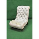 Victorian buttoned slipper chair having scrolled shape and standing on turned feet with castors