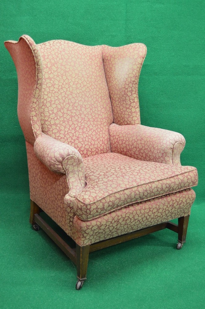 Georgian style upholstered wing back armchair standing on stretchered square tapering legs ending