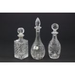 A cut glass decanter with a silver collar, along with two other glass decanters