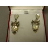 A pair of silver and moonstone owl shaped earrings