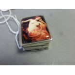 A silver pill box with nude pictorial image to the lid