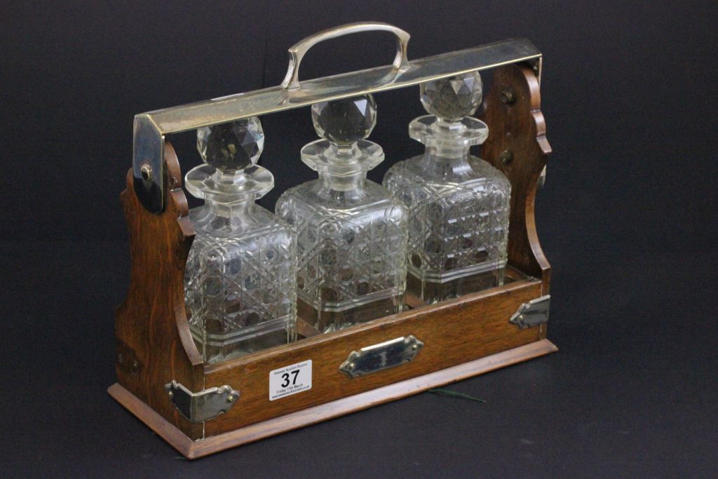 An oak cased tantalus with silver plated mounts and three glass decanters