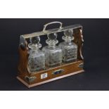 An oak cased tantalus with silver plated mounts and three glass decanters