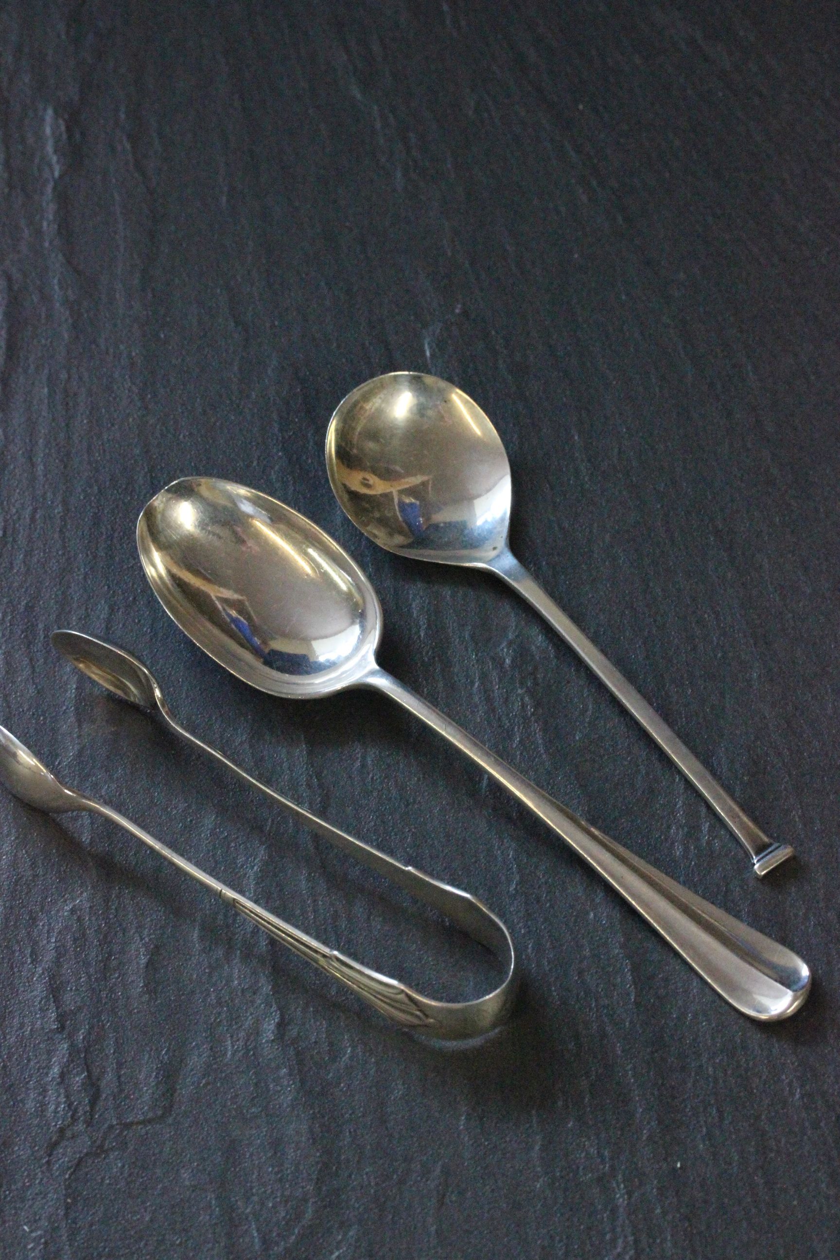 A pair of silver sugar tongs, Sheffield 1902, along with two silver spoons