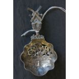 A 19th century Dutch silver tea strainer, decorated with a bird in flight to the bowl, with windmill