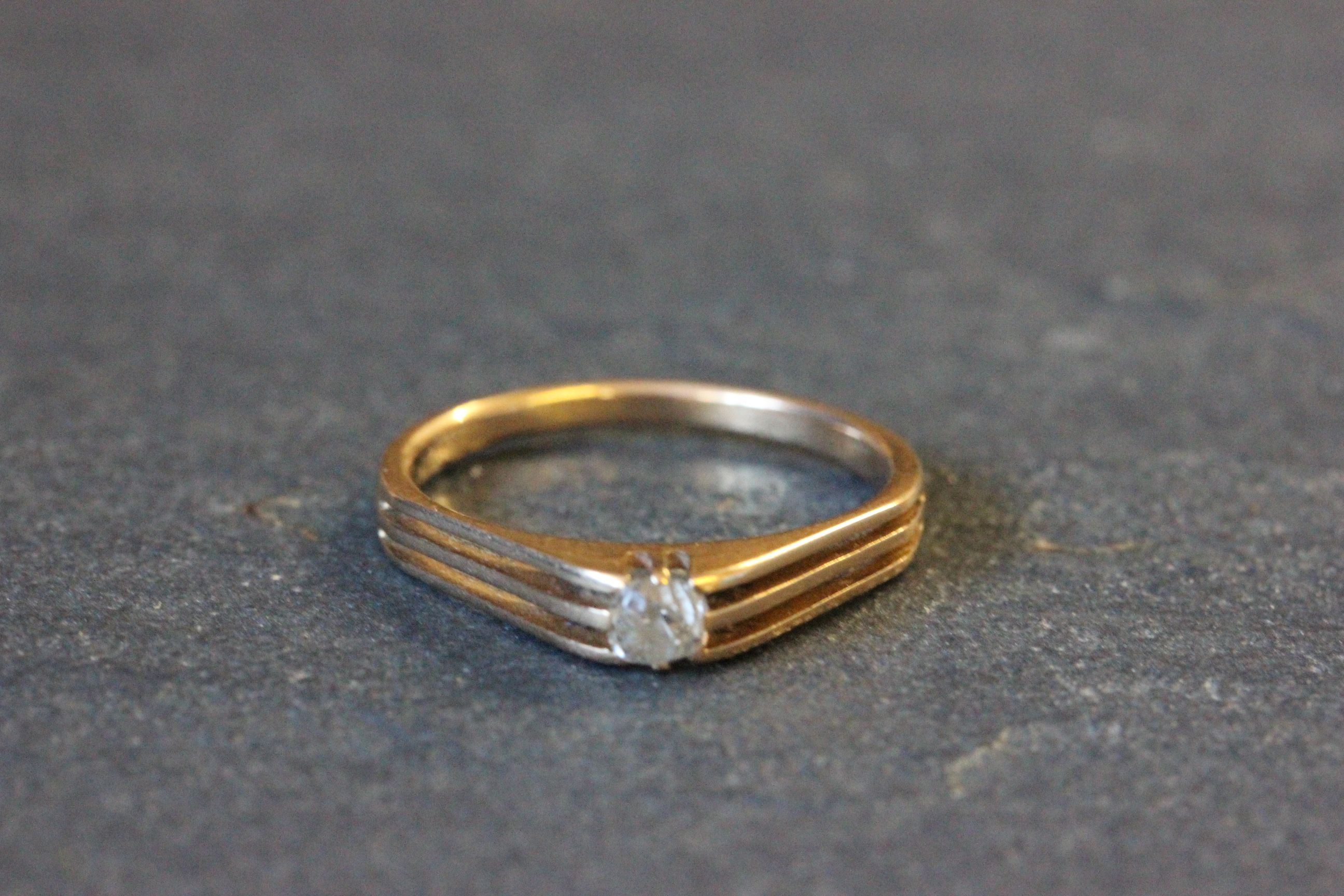 Yellow metal and solitaire diamond ring