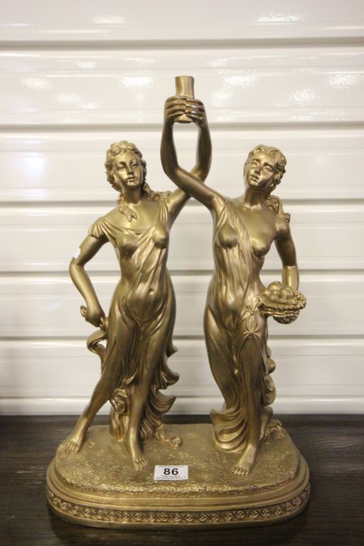 A gilded plaster figure of a couple holding a candle