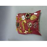 Pillow covered in vintage costume jewellery brooches