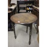 An antique oak cricket table on turned legs