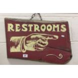 Solid wooden sign with hand painted Restrooms to the front, hanging from a short metal chain