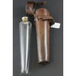 An early 20th century glass flask with silver plated top of tapering form in a leather holder