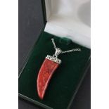 A silver and apple coral pendant necklace in the shape of a tooth