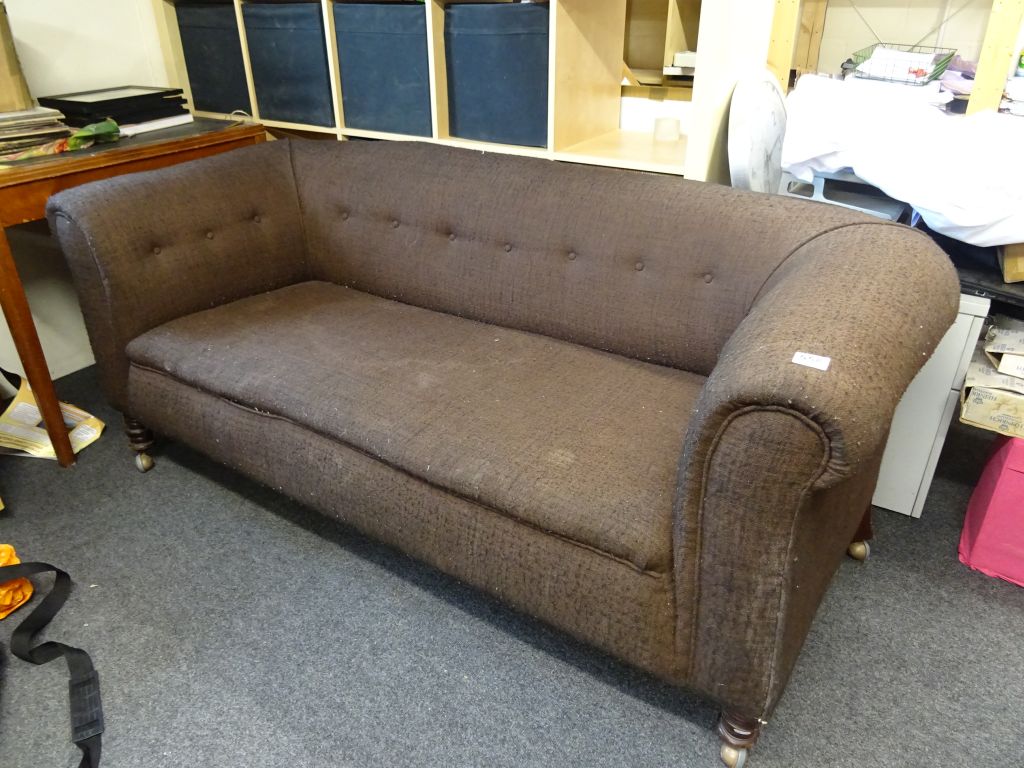 A brown upholstered chesterfield style sofa.