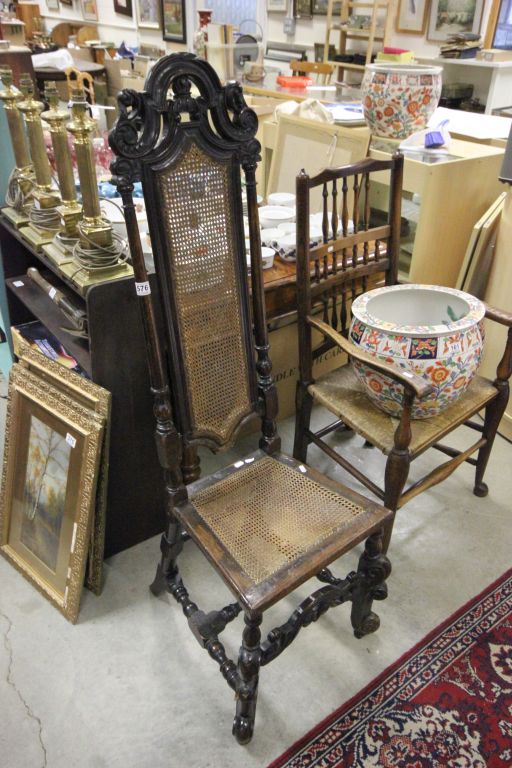 An antique Jacobean oak hall chair of narrow form with rattan seat and back rest .