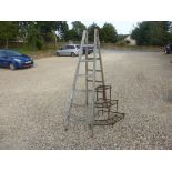 A three tier iron corner plant stand and a rustic set of steps.