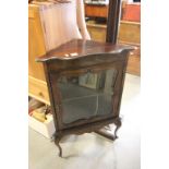 An antique oak corner display cabinet with glazed door raised on cabriole legs.